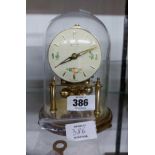 A small vintage Kundo anniversary clock with ball pendulum under glass dome