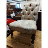 A Victorian low boudoir chair with remains of button back upholstery, set on turned front legs
