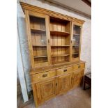 A 1.64m antique waxed pine two part dresser with central open bow front shelves and flanking