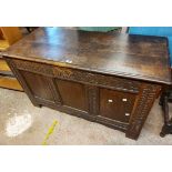 A 1.17m antique oak coffer with carved decoration to triple panel front, set on raise block feet -