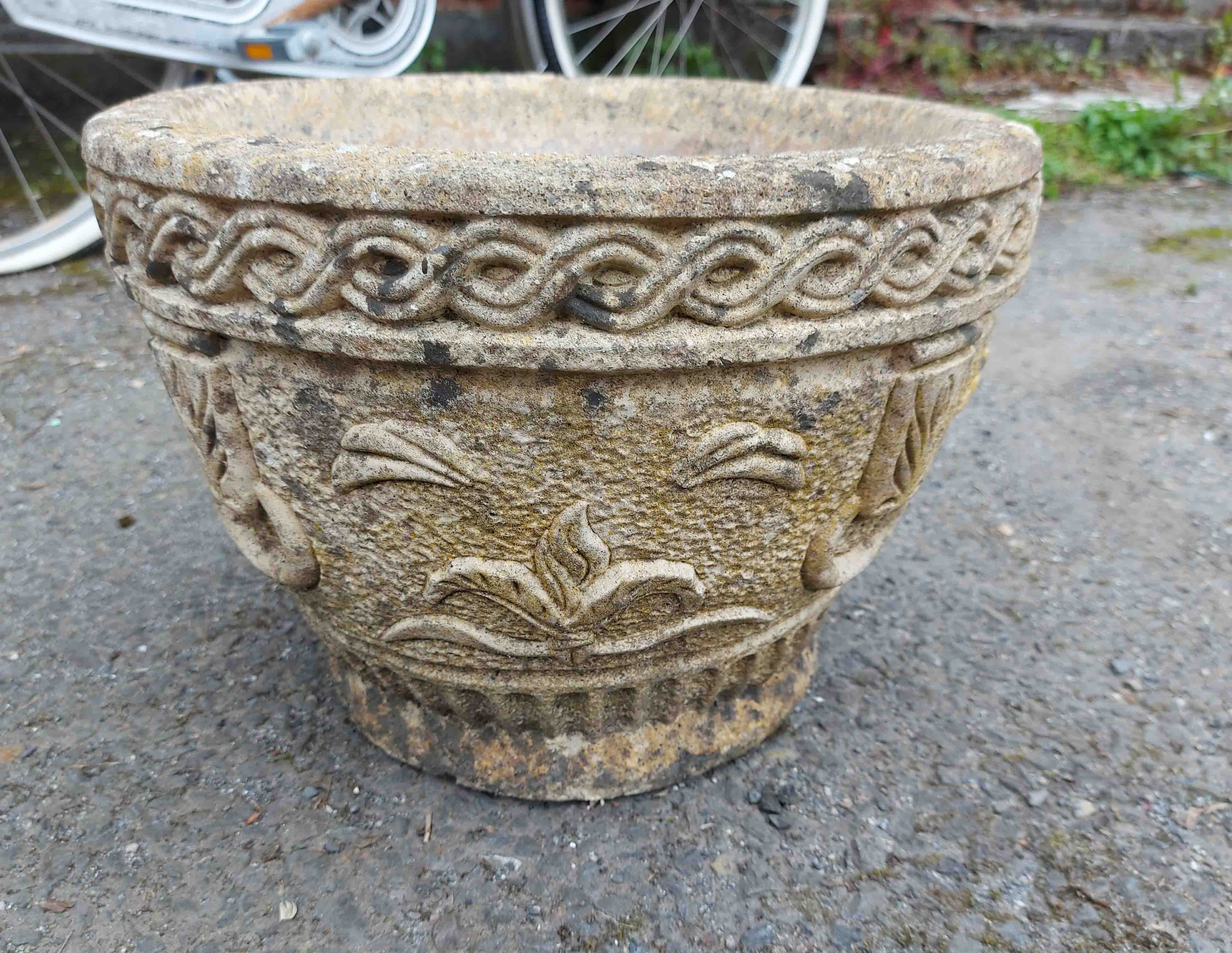 A concrete garden planter of round bowl form, with moulded swag decoration