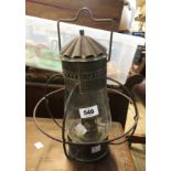 A brass hanging oil lamp of cage form with glass shade