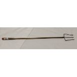 An old toasting fork with turned wooden handle, brass shaft and wirework fork