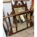 An Edwardian walnut overmantel mirror with decorative pediment, flanking spindle supports and