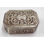 A colonial white metal snuff box of canted oblong form with all-over foliate scroll decoration and