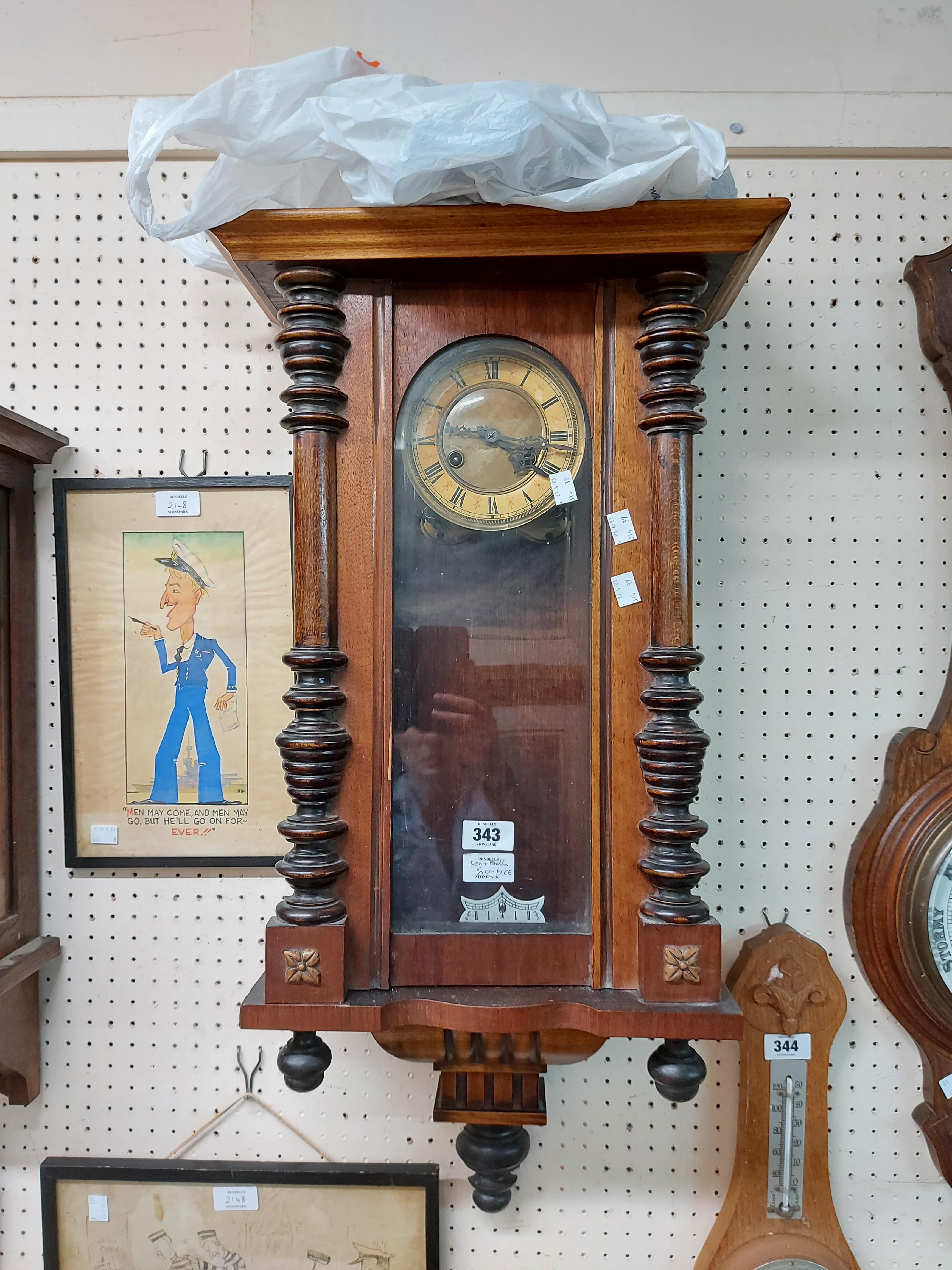 An early 20th Century stained walnut cased Vienna style wall clock with visible pendulum and