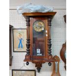 An early 20th Century stained walnut cased Vienna style wall clock with visible pendulum and
