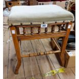 An Edwardian stripped walnut piano stool with studded upholstered seat and spindle set apron, set on