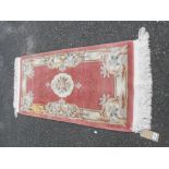 A Chinese washed wool rug with floral motifs on pink ground - 1.45m X 68cm