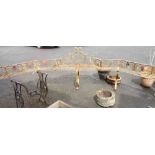 A 3.7m old wrought iron garden seat with canted sides, central pediment and open scroll