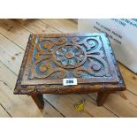 A small late Victorian carved oak stool with roundel and scroll decoration, set on shaped standard