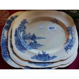 A set of three graduated meat plates with blue transfer printed decoration depicting a river scene