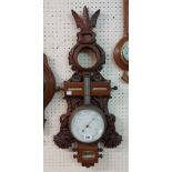 A late 19th Century ornate carved and pierced walnut Black Forest barometer with aperture for
