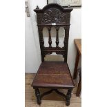 A 20th Century carved oak hall chair with decorative high back and solid seat, set on turned front