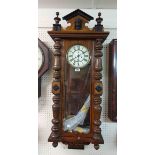 An antique walnut cased Vienna regulator wall clock with decorative pediment, visible pendulum and