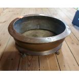 A large old brass oval planter with cast lion paw feet