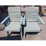 A pair of green painted slatted wood garden elbow chairs