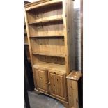 A 92cm modern pine four shelf open bookcase with pair of moulded cupboard doors under, set on
