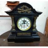 A late Victorian black slate and brass mounted ornate mantel clock with visible escapement to dial