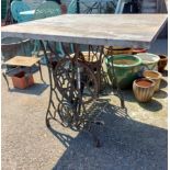 A cast iron Singer sewing machine treadle base, as a table with heavy marbled top