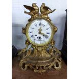 An antique French ornate cast brass cased salon clock with birds to top, flanking garlands and