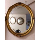A reproduction gilt framed bevelled oval wall mirror with decorative border