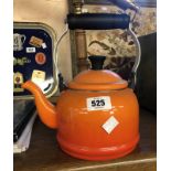 A small Le Creuset enamelled kettle in the orange colourway