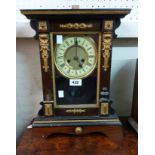 An antique ornate American stained wood and metal detailed cased shelf clock with visible pendulum