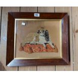 An antique embroidered panel depicting a King Charles spaniel lying on a cushion, set in rosewood