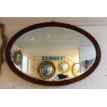 An Edwardian stained walnut and strung framed bevelled oval wall mirror
