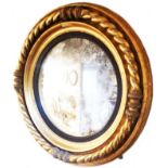 A 71cm diameter late Georgian gilt framed convex wall mirror with reeded ebonised slip border within