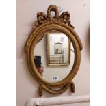 A small vintage Georgian style ornate gilt framed wall mirror with bow pediment and oval plate
