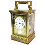 A brass and bevelled glass cased Aiguilles carriage clock with decorative engraved front and