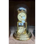 A vintage anniversary clock with Arabic numerals and disc pendulum, under glass dome