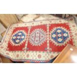 A Turkish handmade wool rug with triple central motifs within a border on red ground - 1.55m X