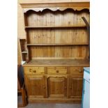 A 1.37m modern pine two part dresser with two shelf open plate rack over a base with three frieze