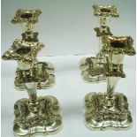 A set of four 18cm Sheffield plate candlesticks with detachable nozzles and loaded shaped bases