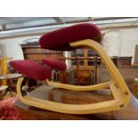 An ergonomic typing chair with burgundy upholstered bentwood frame