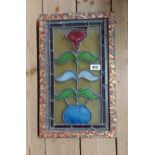 A late 19th/early 20th Century stained glass panel depicting a large flower in a vase with heavily