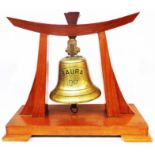 An old phospher bronze ship's bell marked Baura 1917, set on later wooden display stand - salvaged