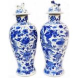 A pair of antique Chinese porcelain lidded jars, each hand painted in blue with dragons amidst