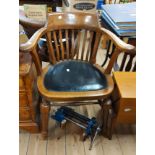 An early 20th Century oak framed lathe back bow elbow chair with black rexine upholstered seat