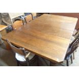 A 1.83m Edwardian oak dining table with now-set top, set on turned legs with brown porcelain