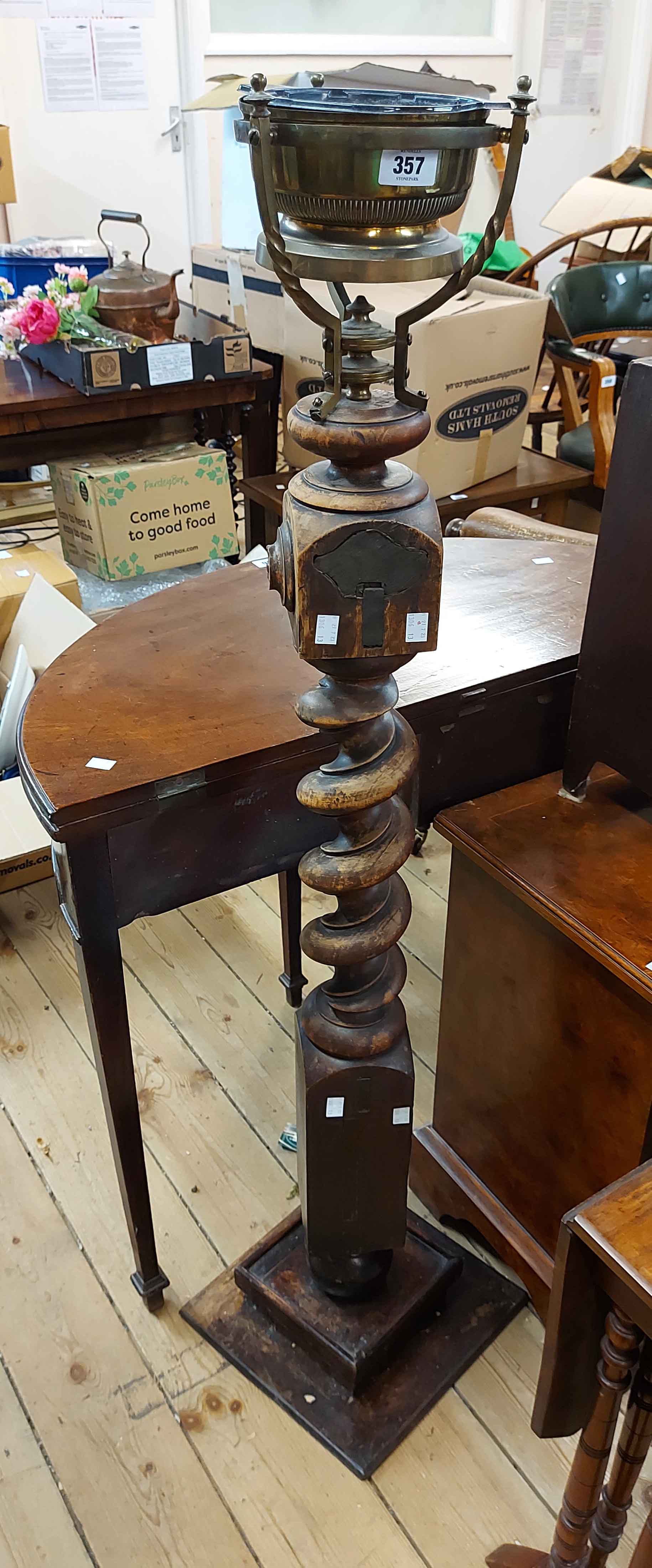 A torchere formed from an antique tester bedpost with brass holder to top and stained wood plinth