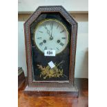 An antique American stained wood cased shelf clock with decorative glazed panel door and bell