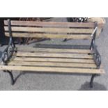 A 1.22m vintage teak garden bench with slatted back and seat, set on wrought iron ends