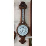 A late Victorian ornate carved oak framed banjo barometer/thermometer with printed ceramic dial