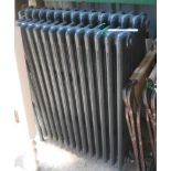 Two similar old freestanding column central heating radiators with dark grey anthracite painted