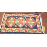A vintage handmade kelim with repeat motifs on blue ground - 1.2m X 67cm