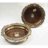 A pair of silver plated copper wine bottle coasters with decorative cast rims and turned wood bases